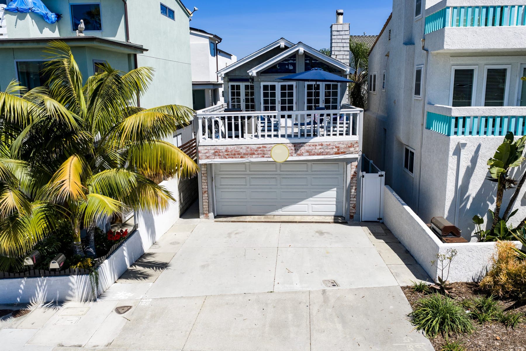 Wide front exterior view of Newport Beach Retreat with driveway parking and upper balcony