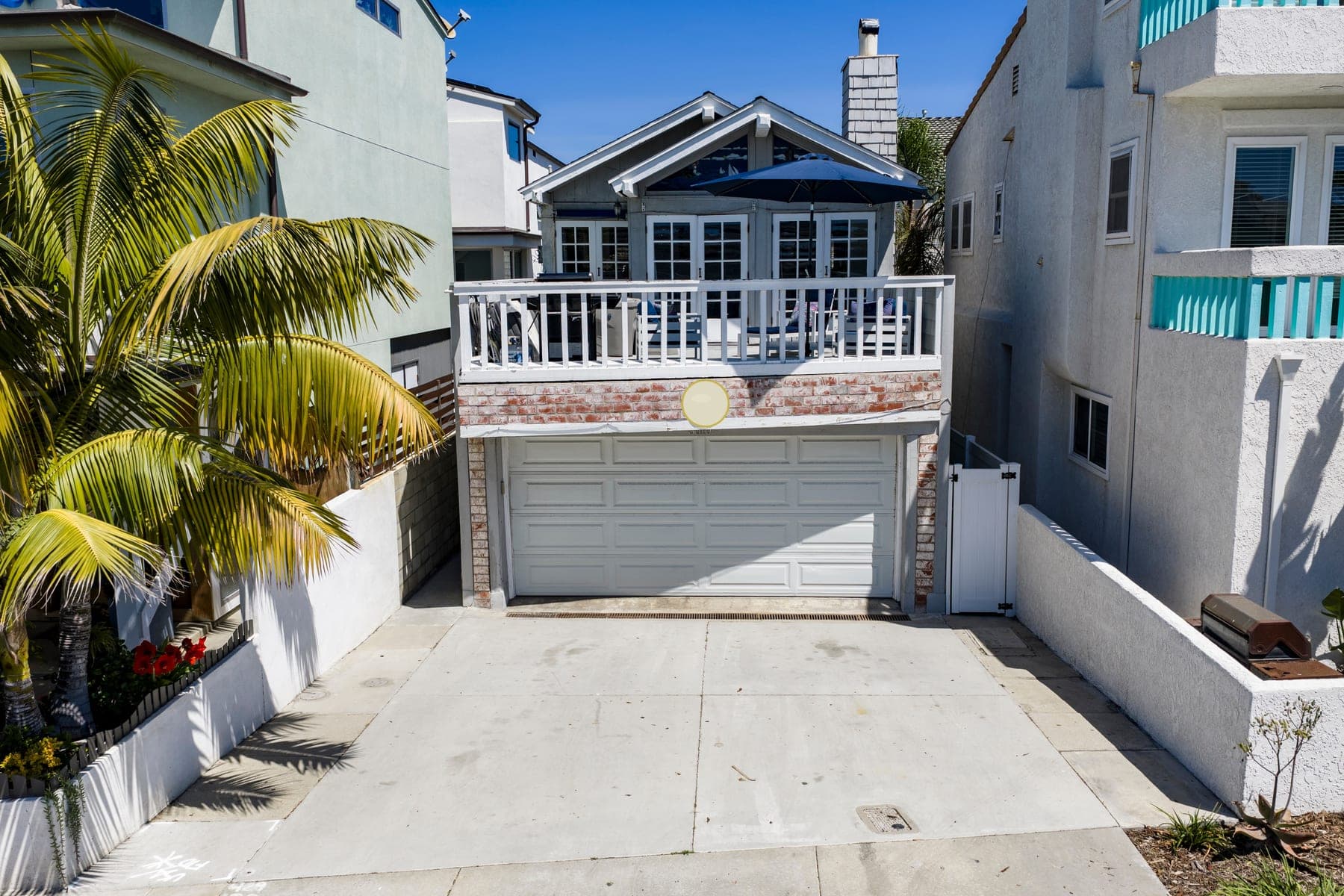 Front exterior of Newport Beach Retreat with driveway parking and balcony deck