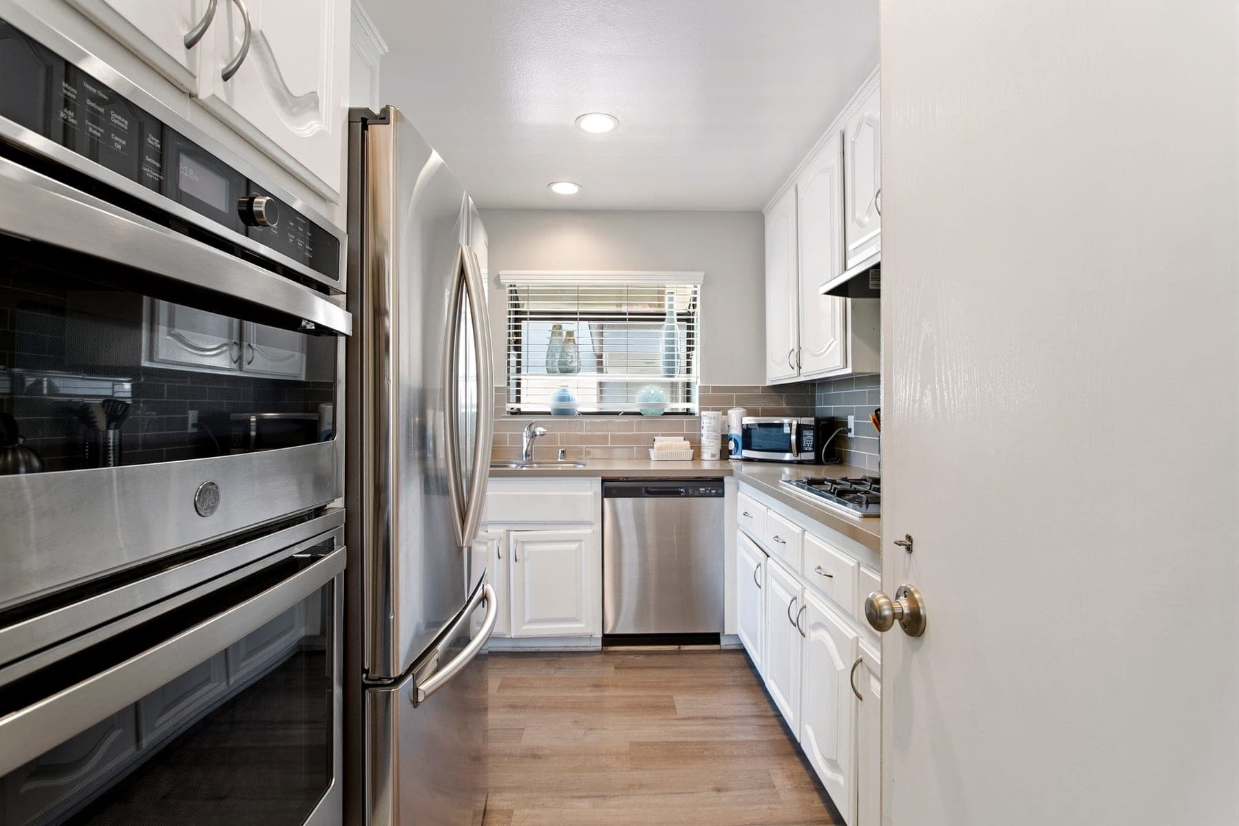 Full kitchen with stainless steel refrigerator and white cabinetry