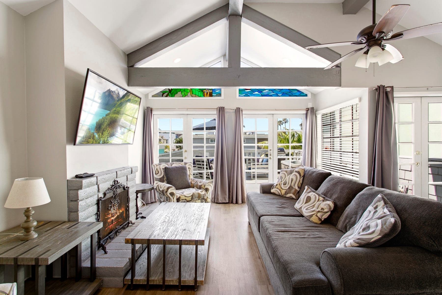 Open living room and kitchen entry with vaulted ceiling and balcony doors