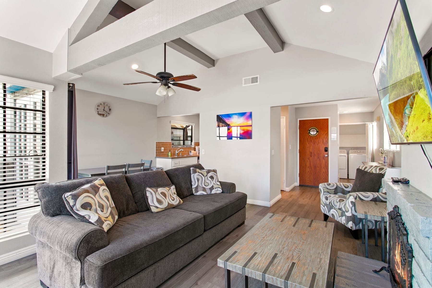 Open living area with sofa, dining space, kitchen pass-through, and entry